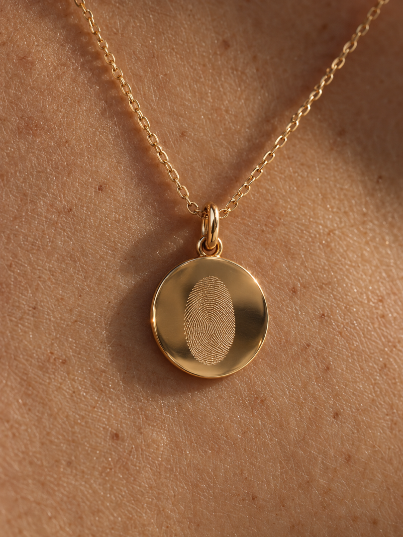 Detalle colgante huella dactilar en oro 18K sostenido con los dedos en escote - Mimmo Jewels